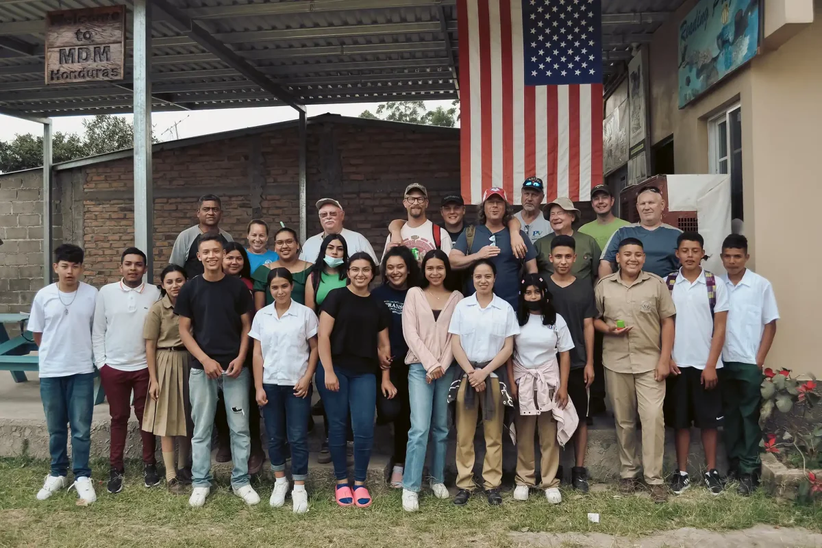 students, mission team members and teachers in front of school