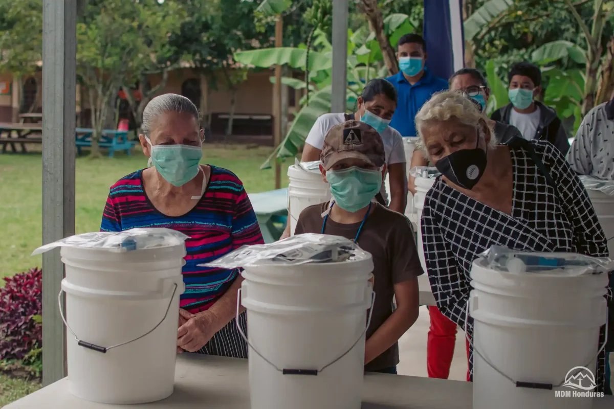 3 women with clean water kits in front of them