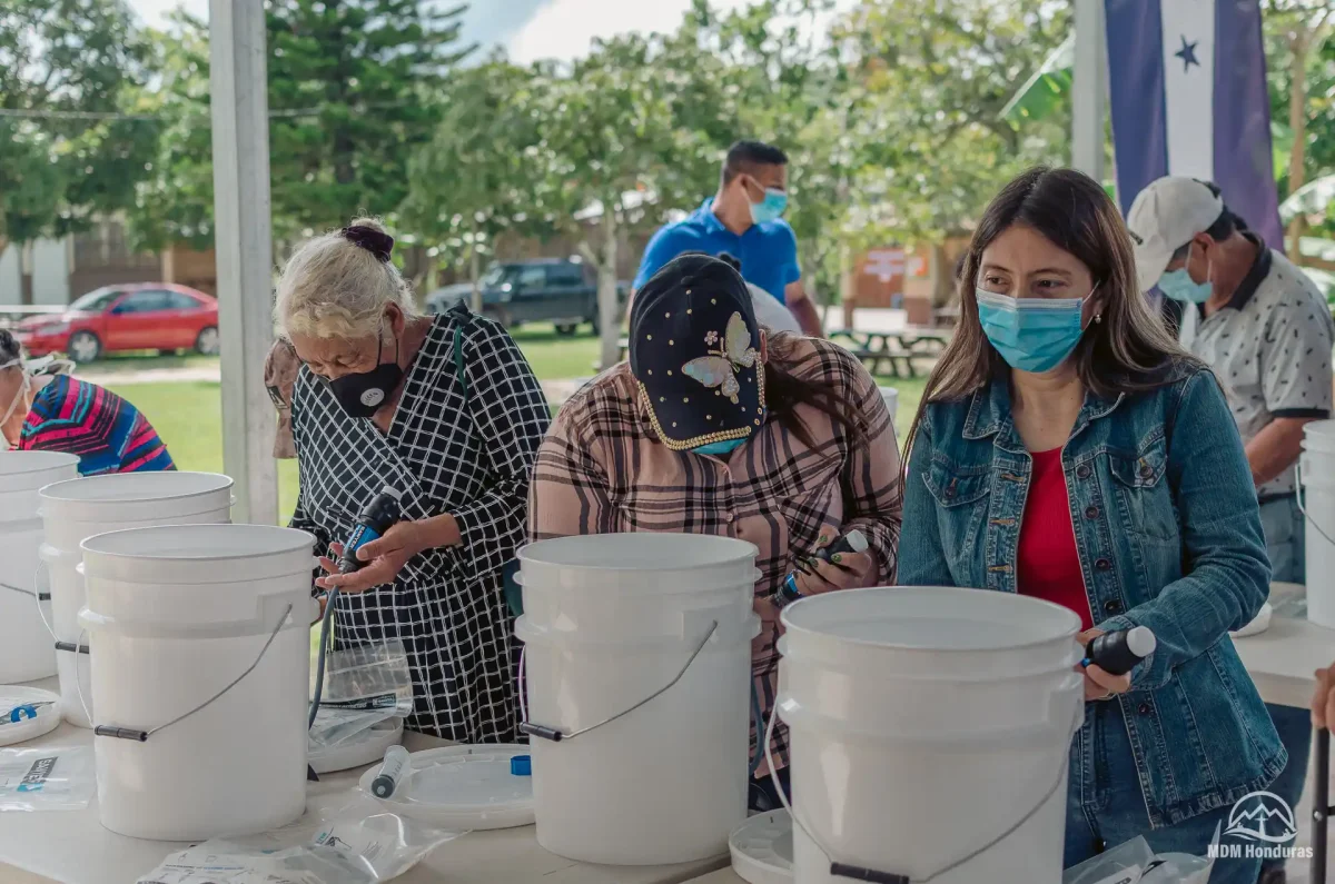 3 women with water buckets on table