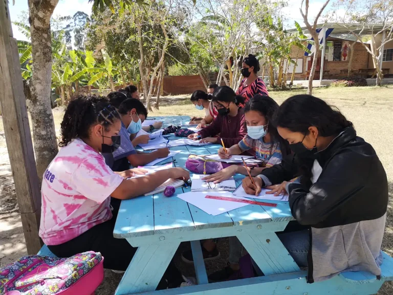 students writing on picnic table